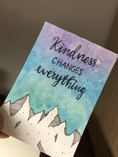 someone holding up a card with the words kindness changes everything on it and mountains in the background