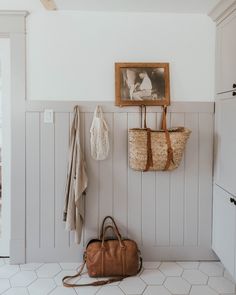 a purse and coat hang on the wall in a white room with wood paneling