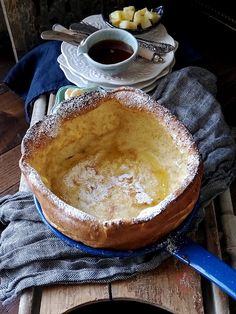 a bowl with some food in it on a table next to plates and spoons