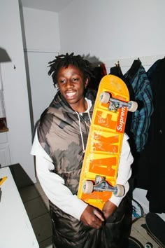 a young man holding a skateboard in his hands and smiling at the camera,