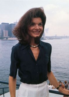 a woman standing on the deck of a boat in front of a large body of water