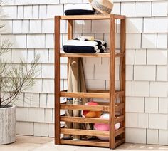 a wooden shelf with towels and hats on it in front of a white brick wall