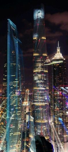 the city skyline is lit up at night with skyscrapers in the foreground and other tall buildings