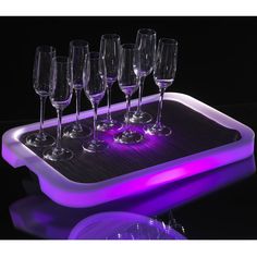 a tray with wine glasses on it and purple light in the middle is lit up