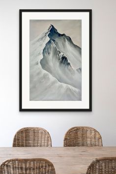 a painting hanging on the wall above a dining room table with wicker chairs and rattan chairs