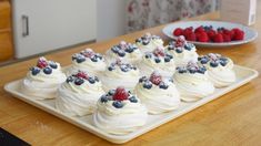 there are many cupcakes with berries on them sitting on the table next to each other