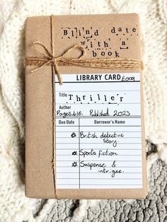 a library card is wrapped in brown paper and tied with twine on top of a white blanket