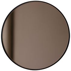 a round mirror with black trim on the bottom and an empty wall in the background