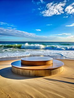 a circular bench sitting on top of a sandy beach next to the ocean with waves coming in