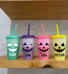 three different colored cups with halloween faces on them, one has a straw and the other has a lid