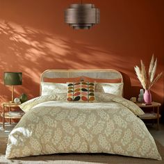 a bed in a bedroom with orange walls and pillows on the headboard, along with two side tables