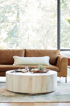 a living room with a couch, coffee table and large window overlooking the trees outside