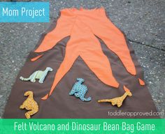 the homemade felt volcano and dinosaur bean bag game is ready to be played on the ground