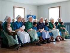 a group of older people sitting next to each other in front of a wall with windows