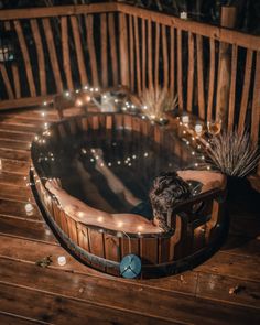 a person sitting in a hot tub with candles on the side and lights around it