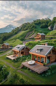 a group of wooden cabins sitting on top of a lush green hillside