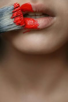 a woman's lips are painted red and white with the brush in her mouth