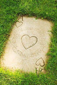 two hearts drawn in the grass on top of a stone