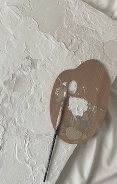 an artist's palette and brush resting on a white sheet with paint chippings