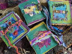 several square pieces of colorful fabric on a rug with beads and threads hanging from them