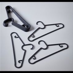 four pieces of black metal hangers on a white surface