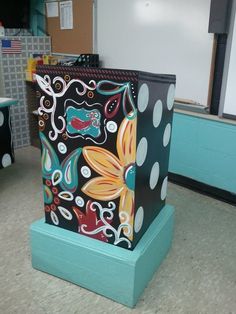 a black and white polka dot bag sitting on top of a blue stand in front of a chalkboard