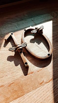 a wooden cross sitting on top of a hard wood floor next to a shadow from the sun