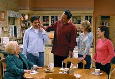 a group of people standing around a kitchen table