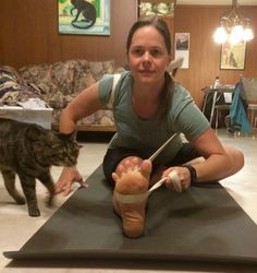 a woman sitting on top of a mat next to a cat