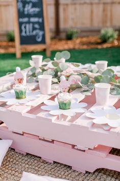 a pink table with cupcakes and plates on it