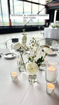 a table with white flowers and candles on it