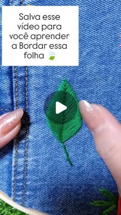 someone is stitching a green leaf on the back of a pair of blue jeans