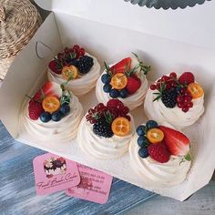 there are many small cakes with fruit on them in the box and one has a tag