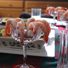 there are shrimp in the wine glass on the table with other dishes and glasses around it