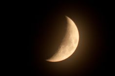 the moon is seen in front of a dark sky with only one light on it