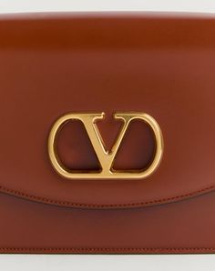 Valentino Garavani Vain shoulder bag in shiny calfskin with metallic VLogo Signature detail. The bag can be carried on the shoulder/cross body thanks to the sliding chain. - Antique gold-finish hardware - Magnetic closure with antique brass-finish VLogo - Nappa lining. Interior: two compartments, zip pocket and slip pocket Shoulder strap drop length: min. 27 cm - 52 cm max. / min. 10.6 cm to max. 20.4 in. - Dimensions: W24xH16xD8 cm / W9.4xH6.2xD0.7 in. - Made in Italy This product contains magn Luxury Tan Crossbody Shoulder Bag, Elegant Brown Shoulder Bag With Metal Logo, Modern Gold Shoulder Bag With Logo, Formal Logo Satchel Shoulder Bag, Luxury Brown Shoulder Bag With Logo, Classic Gold Shoulder Bag With Logo, Brown Luxury Shoulder Bag With Logo, Formal Brown Shoulder Bag With Gold-tone Logo Plaque, High-end Leather Shoulder Bag With Logo