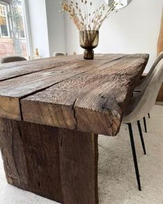 a wooden table with chairs around it and a vase on the table next to it