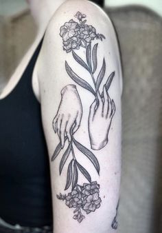 a woman's arm with flowers and two hands holding each other on her shoulder