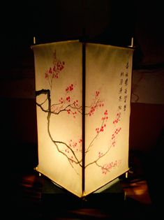 a lamp that is lit up in the dark with red flowers on it and branches