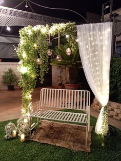 a white bench sitting in the middle of a lush green yard with lights on it