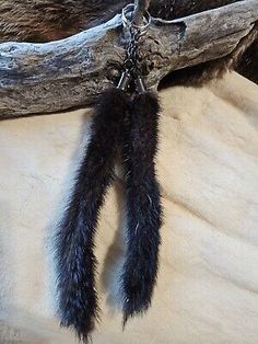 an animal's tail is hanging from a piece of wood with chains attached to it