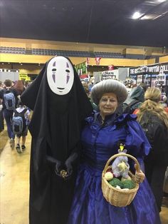 a woman in a blue dress holding a basket and wearing a ghost mask with her arms around her neck