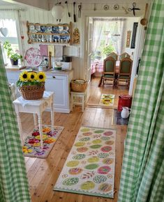 a kitchen with green and white checkered curtains, sunflowers on the rug