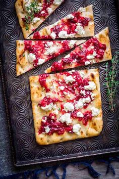 four slices of flatbread pizza with cheese and cranberry sauce on a serving tray