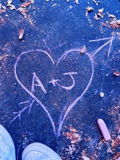 someone's feet are standing in front of a heart with an arrow drawn on it