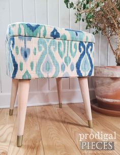 a blue and white ottoman sitting on top of a wooden floor next to a potted plant