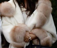 a woman wearing a fur coat and holding a handbag