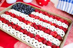 an american flag made out of pretzels and strawberries on a red white and blue table cloth