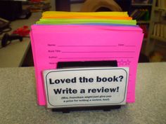 a stack of pink folders sitting on top of a counter next to a pile of books