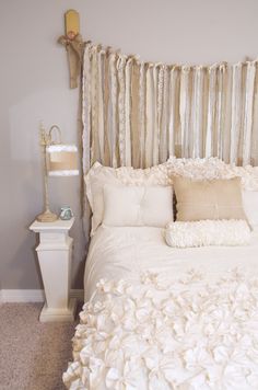 a white bed topped with lots of pillows next to a night stand and nightstands